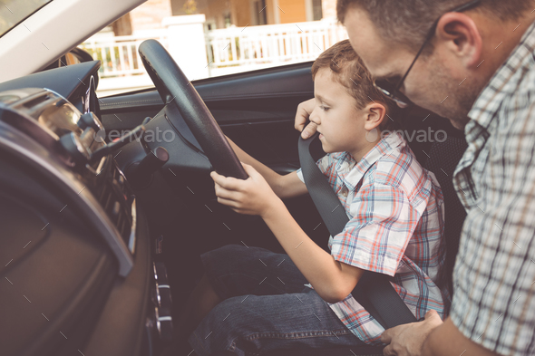 Happy father and son sitting in the car at the day time. Stock Photo by altanaka