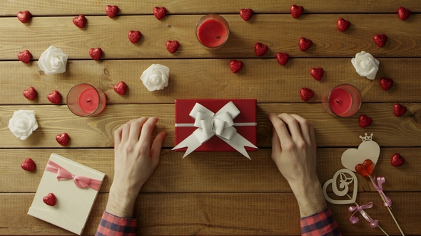 Man Puts Valentine Onto Present Box for His Loved One, Top View