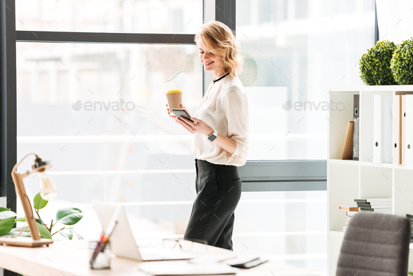 Amazing young business woman chatting by mobile phone drinking coffee. Stock Photo by vadymvdrobot