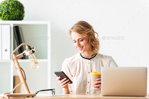 Smiling young business woman chatting by mobile phone drinking coffee. - Stock Photo - Images