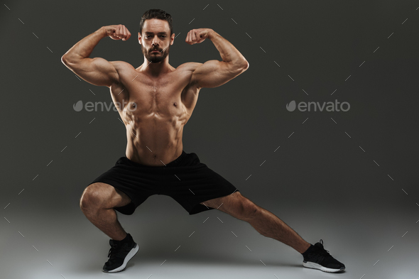 Smiling fitness woman show her biceps at gym Stock Photo by vadymvdrobot