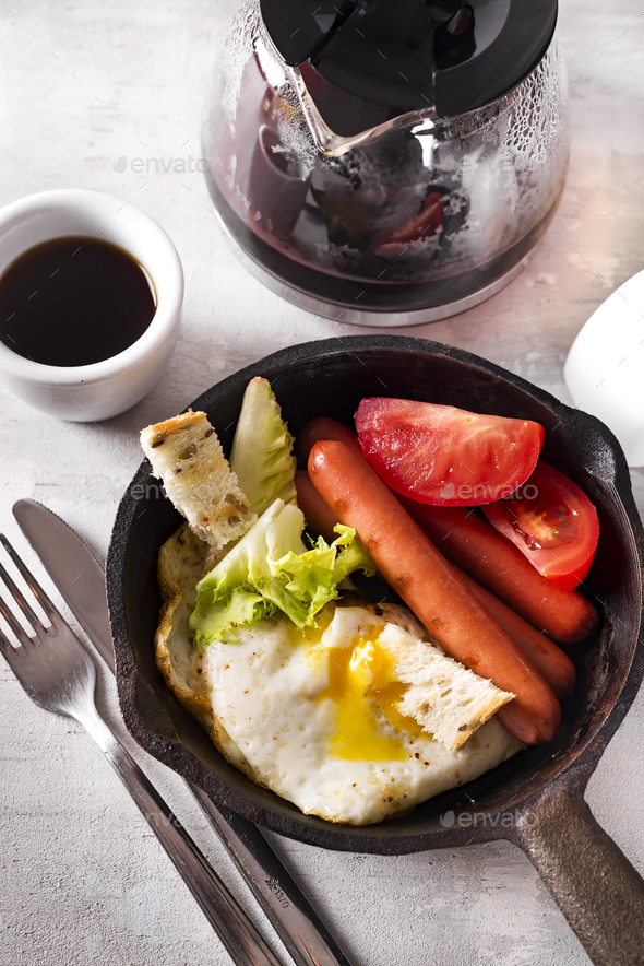 Homemade delicious american breakfast with fried egg, toast, sausage, vegetable, black coffee - Stock Photo - Images
