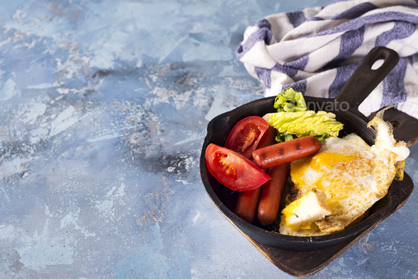 Homemade delicious breakfast on a pan with fried egg, toast, sausage, vegetable, black coffee - Stock Photo - Images