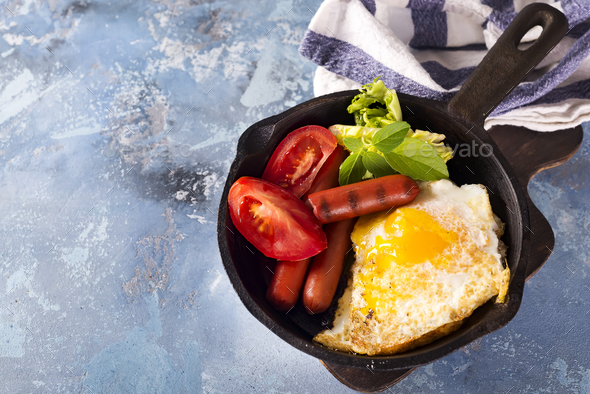 Homemade delicious breakfast on a pan with fried egg, toast, sausage, vegetable, black coffee - Stock Photo - Images