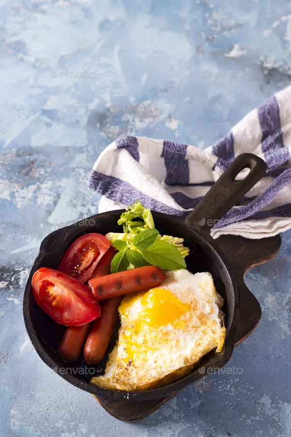 Homemade delicious breakfast on a pan with fried egg, toast, sausage, vegetable, black coffee - Stock Photo - Images