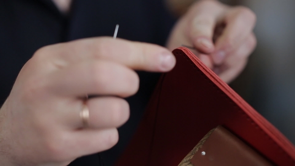 Man Creates a Brown Leather Wallet with His Own Hands with a Needle in the Leather Workshop,