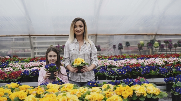 Smiling Adult and Young Girls Stretching Flower Pots to Camera alt