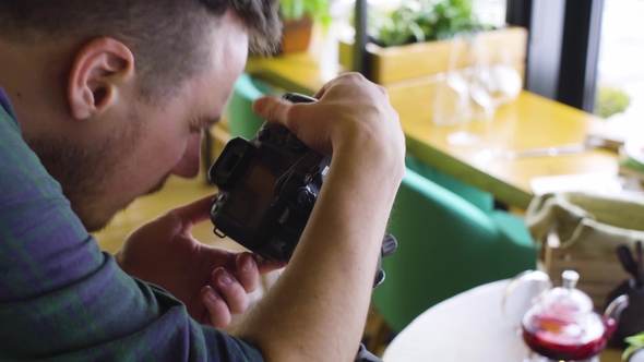 Tripod Shot of Man Using Digital Camera and Making Photos of Food on Wood Table alt