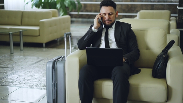 Tilt Up of Confident Attractive Businessman Talking Mobile Phone and Using Laptop Computer While alt