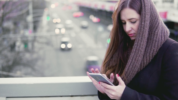 Young Woman Uses a Smartphone in the City