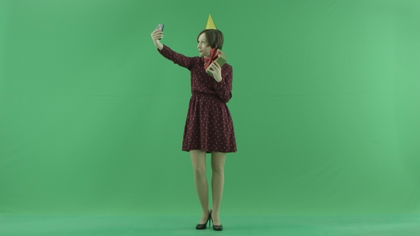 A Young Woman Is Making Selfies with Her Gift on the Green Screen