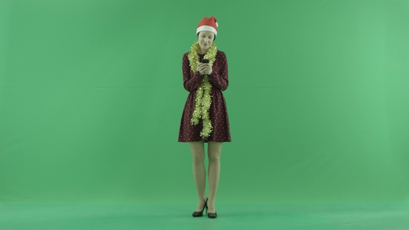 A Young Christmas Woman Is Writing Something with Her Phone on the Green Screen