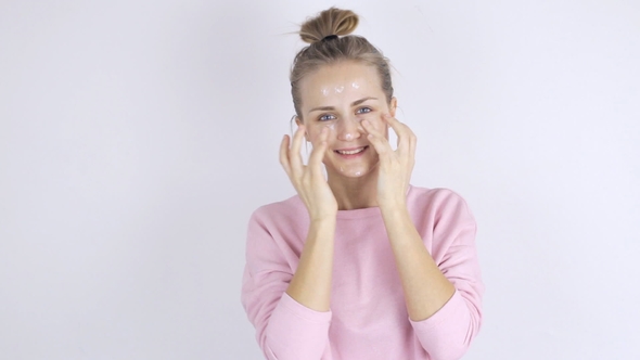 Young Beautiful Woman Applying Cream on Her Face. Skincare Concept