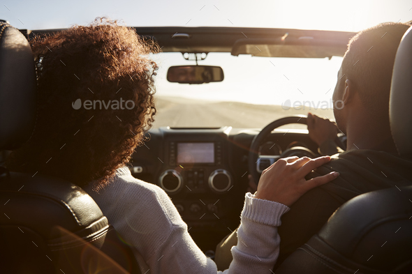 Black couple driving, her hand on his shoulder, back view Stock Photo by monkeybusiness