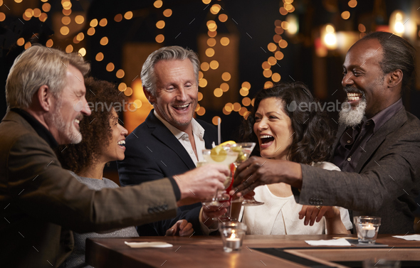 Group Of Middle Aged Friends Celebrating In Bar Together Stock Photo by monkeybusiness