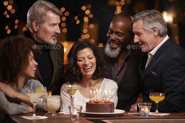 Group Of Middle Aged Friends Celebrating Birthday In Bar Stock Photo by monkeybusiness