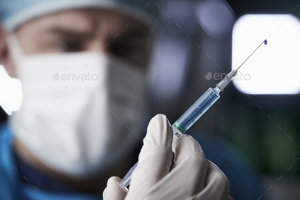 Male healthcare worker preparing syringe, close up Stock Photo by monkeybusiness