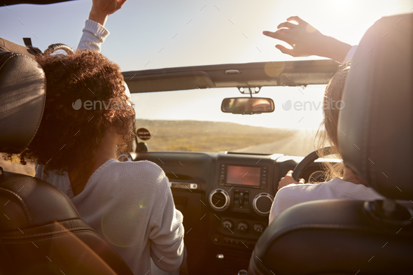 Young adult girlfriends driving with sunroof open, back view Stock Photo by monkeybusiness