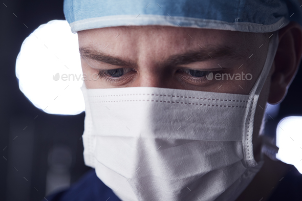 Male healthcare worker in scrubs, head shot, looking down Stock Photo by monkeybusiness