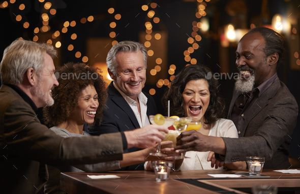 Group Of Middle Aged Friends Celebrating In Bar Together Stock Photo by monkeybusiness