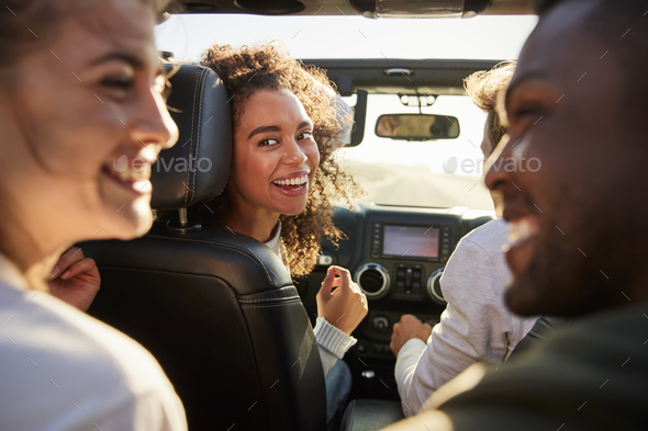 Four young adult friends in a car on a road trip together Stock Photo by monkeybusiness