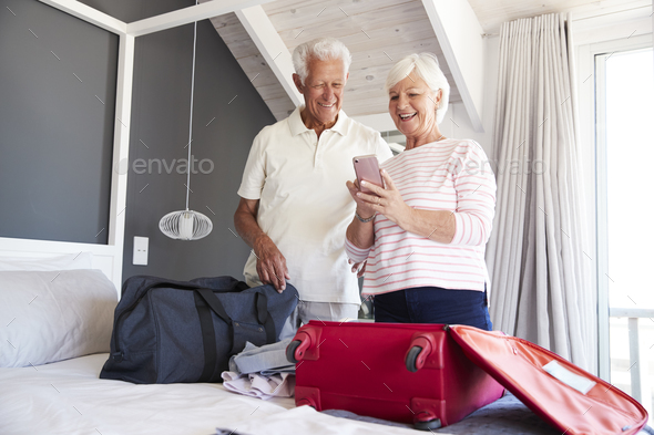 Senior Couple Look At Mobile As They Check In To Vacation Rental Stock Photo by monkeybusiness