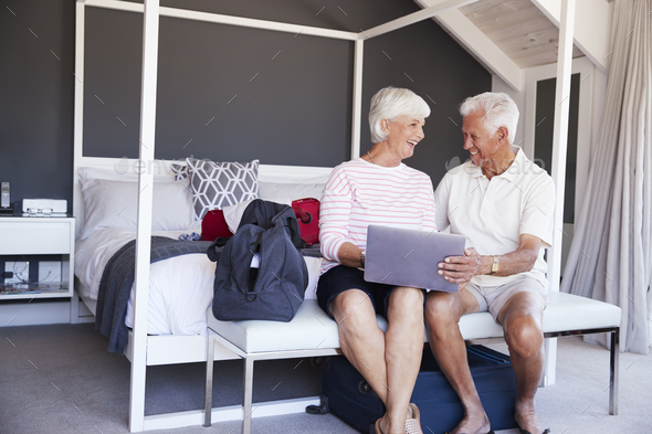 Senior Couple Look At Laptop As They Check In To Vacation Rental Stock Photo by monkeybusiness