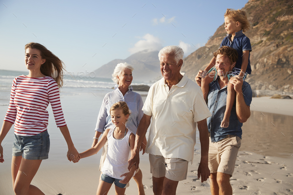 Multi Generation Family On Vacation Walking Along Beach Together Stock Photo by monkeybusiness