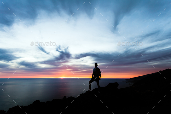 Celebrating or meditating man looking at sunset ocean - Stock Photo - Images