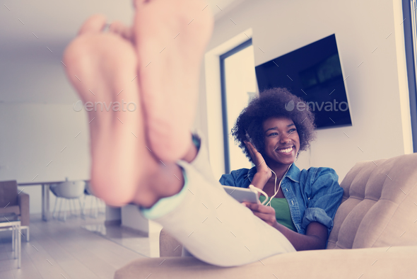 African american woman at home in chair with tablet and head pho - Stock Photo - Images