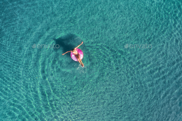 Aerial view of young woman swimming on the pink swim ring Stock Photo ...