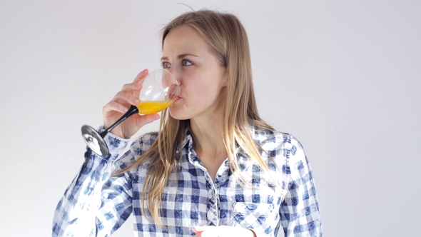 Beautiful Young Girl Smiles at the Camera and Drinks Orange Juice
