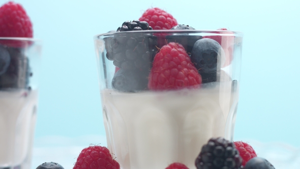 Transparent Glasses Full of Yogurt, Panna Cotta, White Vanilla Mousse Decorated with Berries