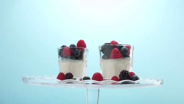 Transparent Glasses Full of Yogurt, Panna Cotta, White Vanilla Mousse Decorated with Berries
