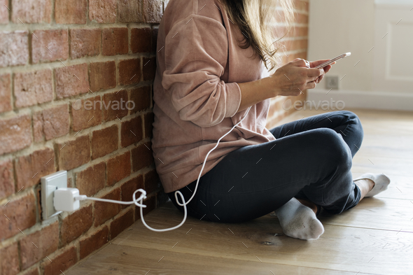 Young woman using a smartphone as it is being charged Stock Photo by Rawpixel