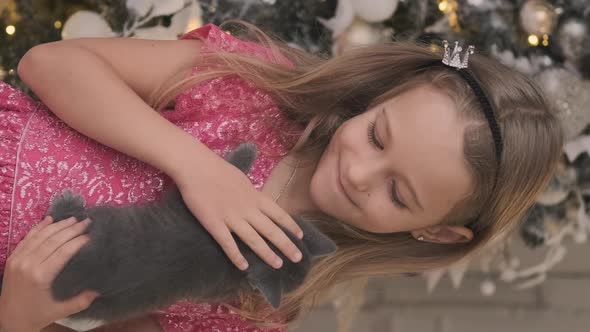 Happy Little Girl Holds Kitten By Xmas Tree alt