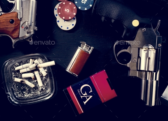 Guns, cigarettes, gambling coins on a table - Stock Photo - Images
