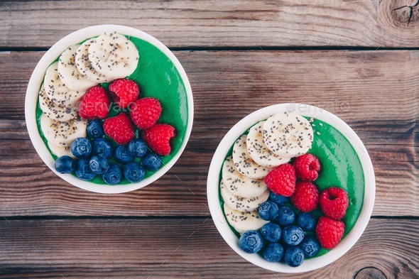 Healthy breakfast smoothies bowl with spirulina powder, banana, raspberries and blueberries Stock Photo by nblxer