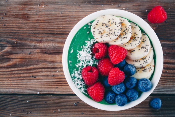 Healthy breakfast smoothies bowl with spirulina powder, banana, raspberries and blueberries Stock Photo by nblxer