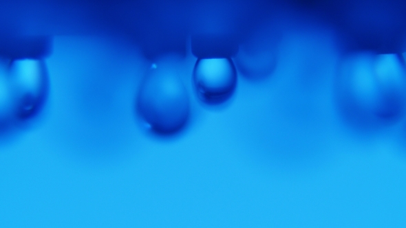 Crystalline Drops of Water Pouring From a Metallic Nozzle in an Arty Blue Bathroom
