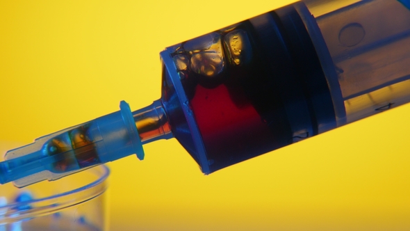Medical Syringe Pulls in Red Blood From a Plastic Cup in a Pharmacy Laboratory