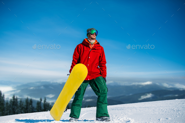 Snowboarder in glasses poses with board in hands - Stock Photo - Images