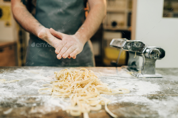 Chef against table with fettuccine, pasta machine - Stock Photo - Images
