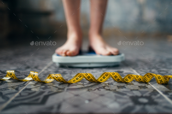 Female feet on the scales, measuring tape Stock Photo by NomadSoul1