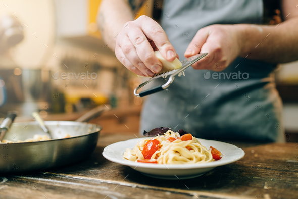 Chef grates cheese to the plate with fresh pasta - Stock Photo - Images