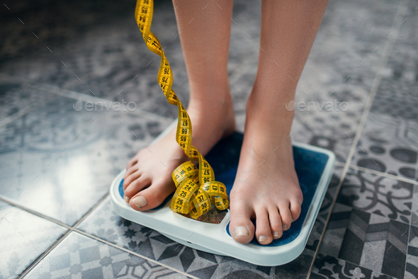 Female feet on the scales closeup, measuring tape Stock Photo by NomadSoul1