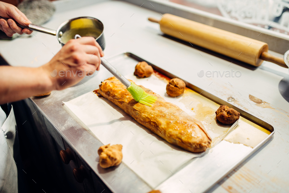 Chef lubricates strudel, preparation for baking - Stock Photo - Images