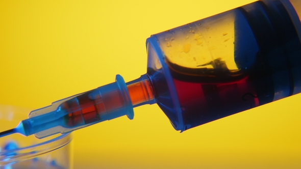 Red Blood Is Squeezed Out From a Medical Syringe in a Plastic Cup in Laboratory