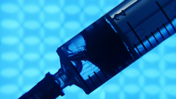 Plastic Syringe Pulls in Water From a Thin Pipe in a Blue Pharmacy Laboratory