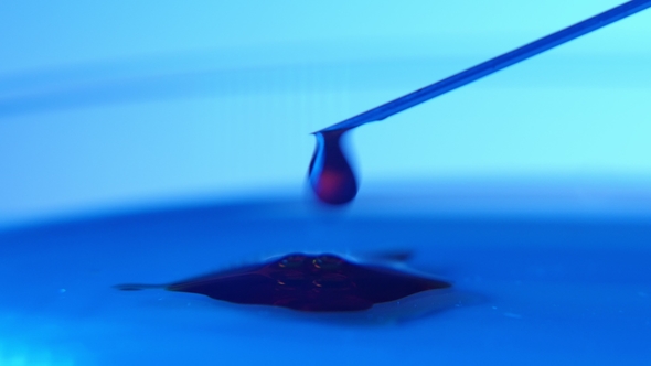Small Drops of Blood Fall From a Metallic Needle on a Blue Glass Surface in a Lab